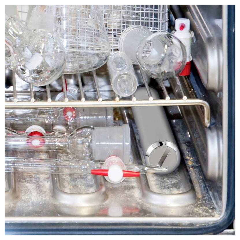 Open dishwasher drawer filled with glassware and bottles on the racks.