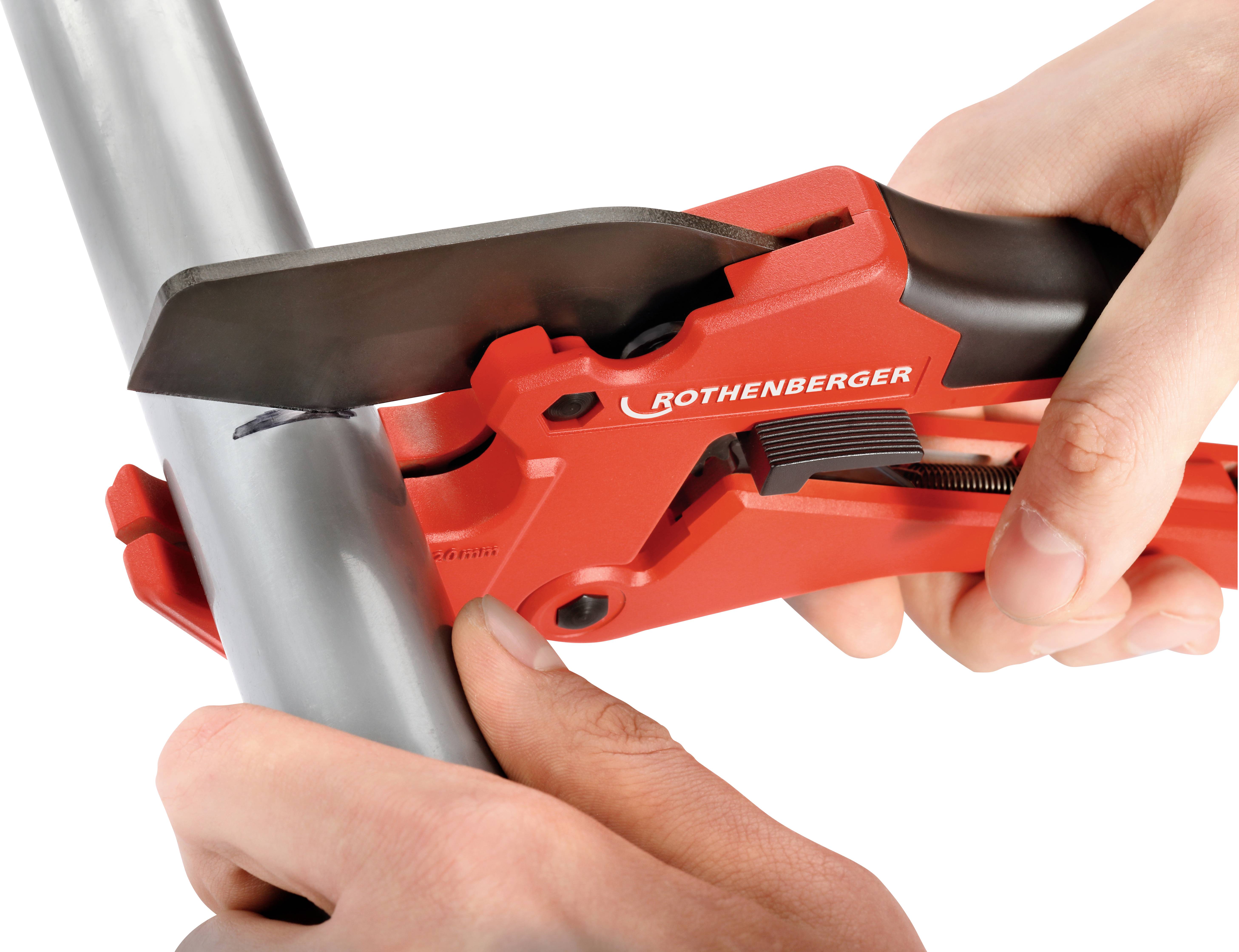 Two hands are using a red pipe cutter to cut a grey pipe. Brand name visible on the tool.