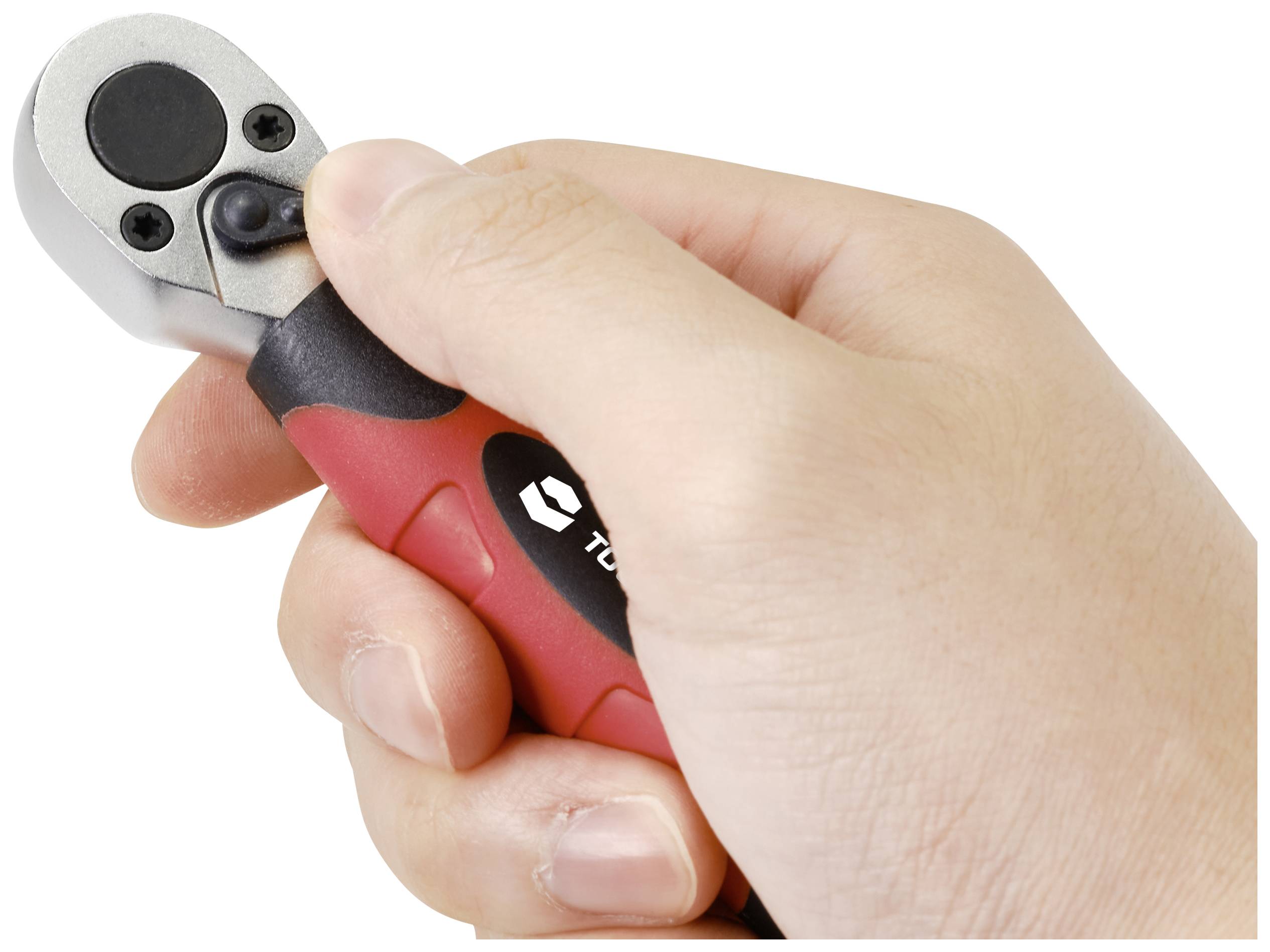 A hand is holding a small ratchet spanner with a red and black handle.