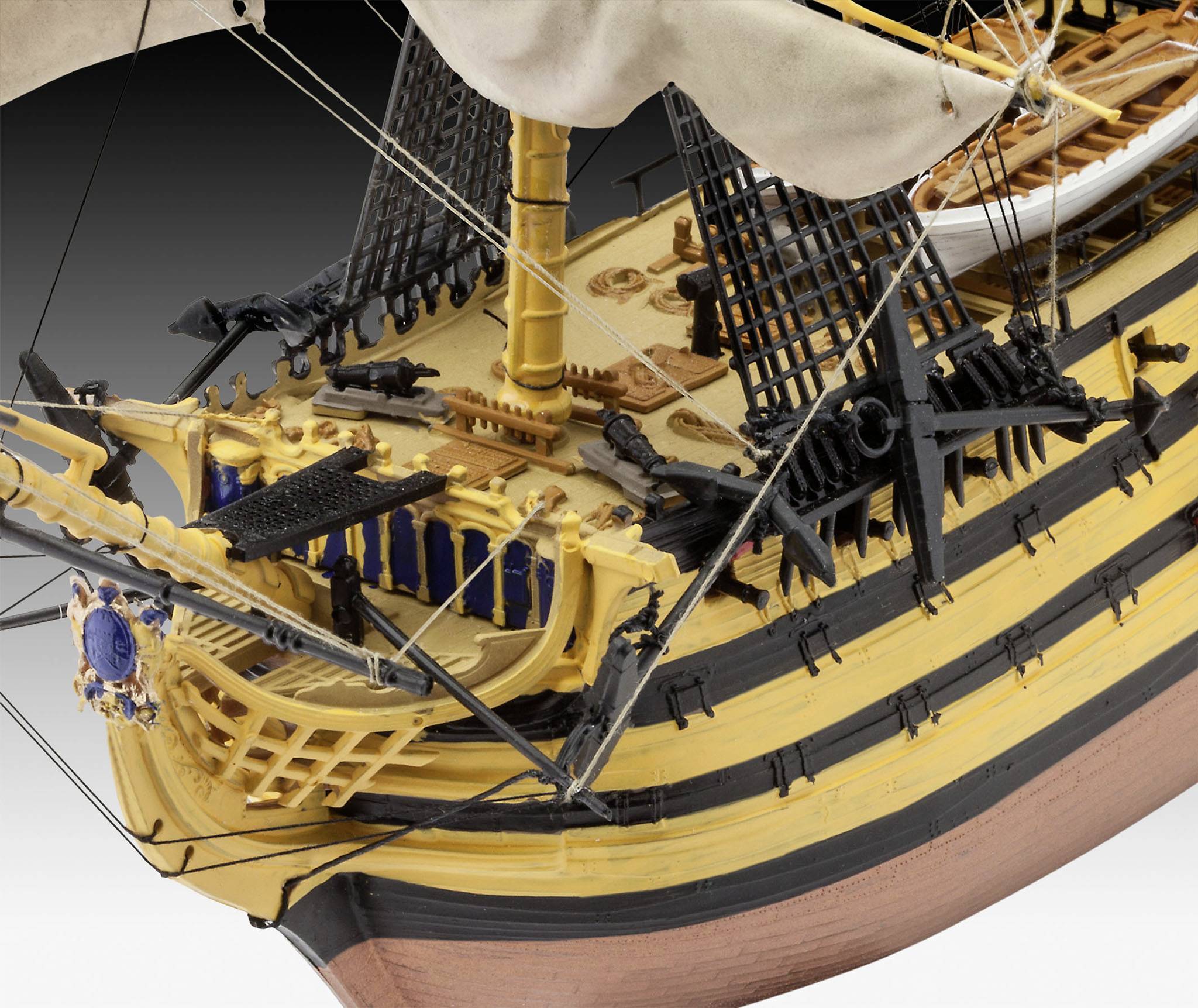 A detailed model of a historic sailing ship. The bow displays an intricately decorated railing and numerous rigging elements.