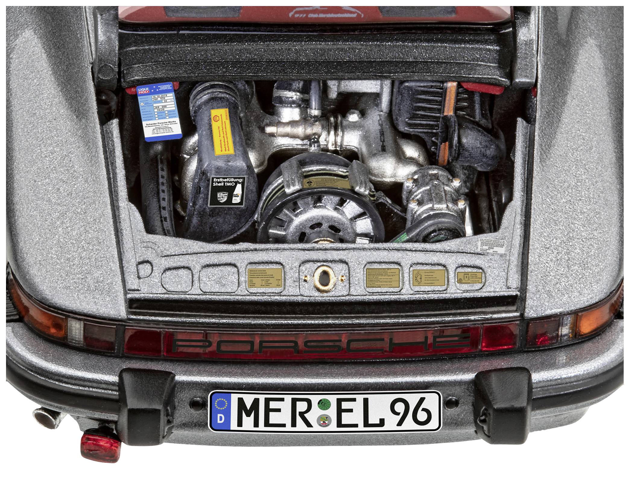 An open engine bay of a grey sports car with the engine visible, with a German number plate reading 'MER EL 96' underneath.