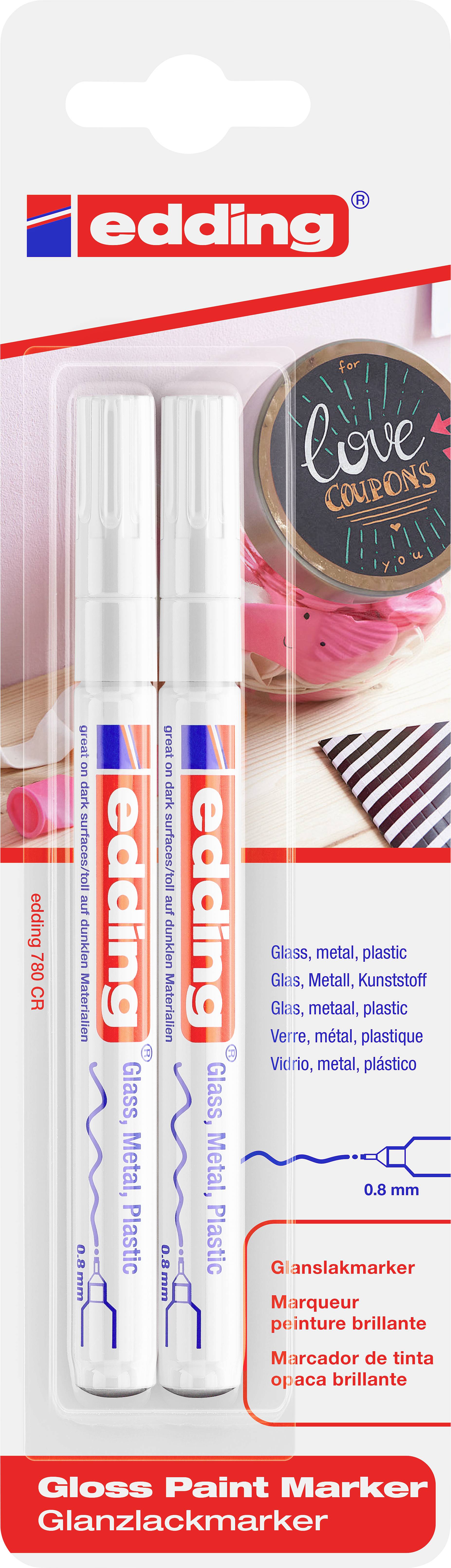 Two white glossy paint markers by the brand 'edding' in a blister pack, with usage examples on various surfaces such as glass and metal.