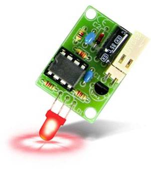 A green electronic module with a microchip, capacitors, and a red illuminated LED emitting light downwards.