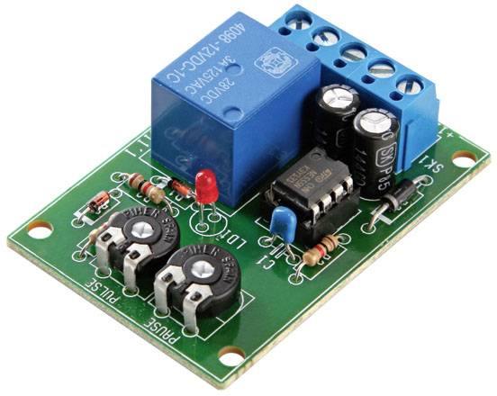 A green printed circuit board with a blue relay module, capacitors, resistors, and a red LED light on it.