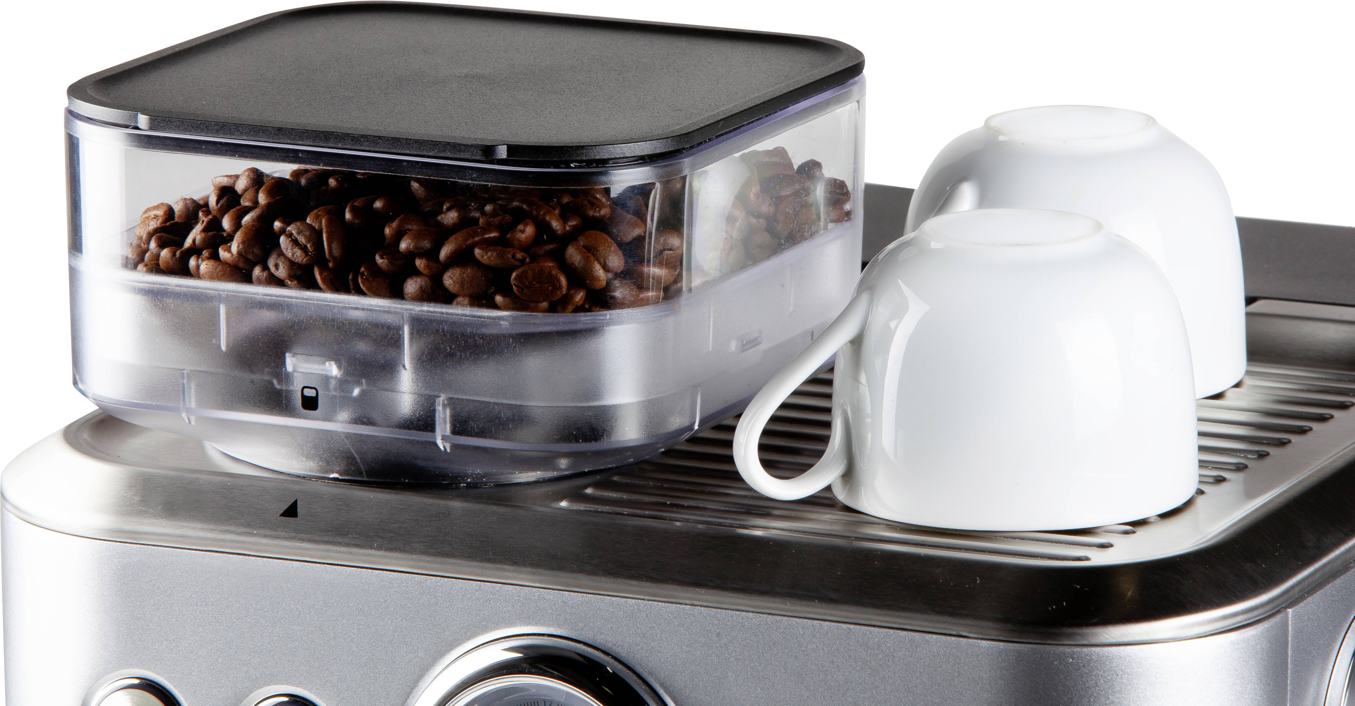 A coffee machine with coffee beans in the container and two empty white cups on the casing.