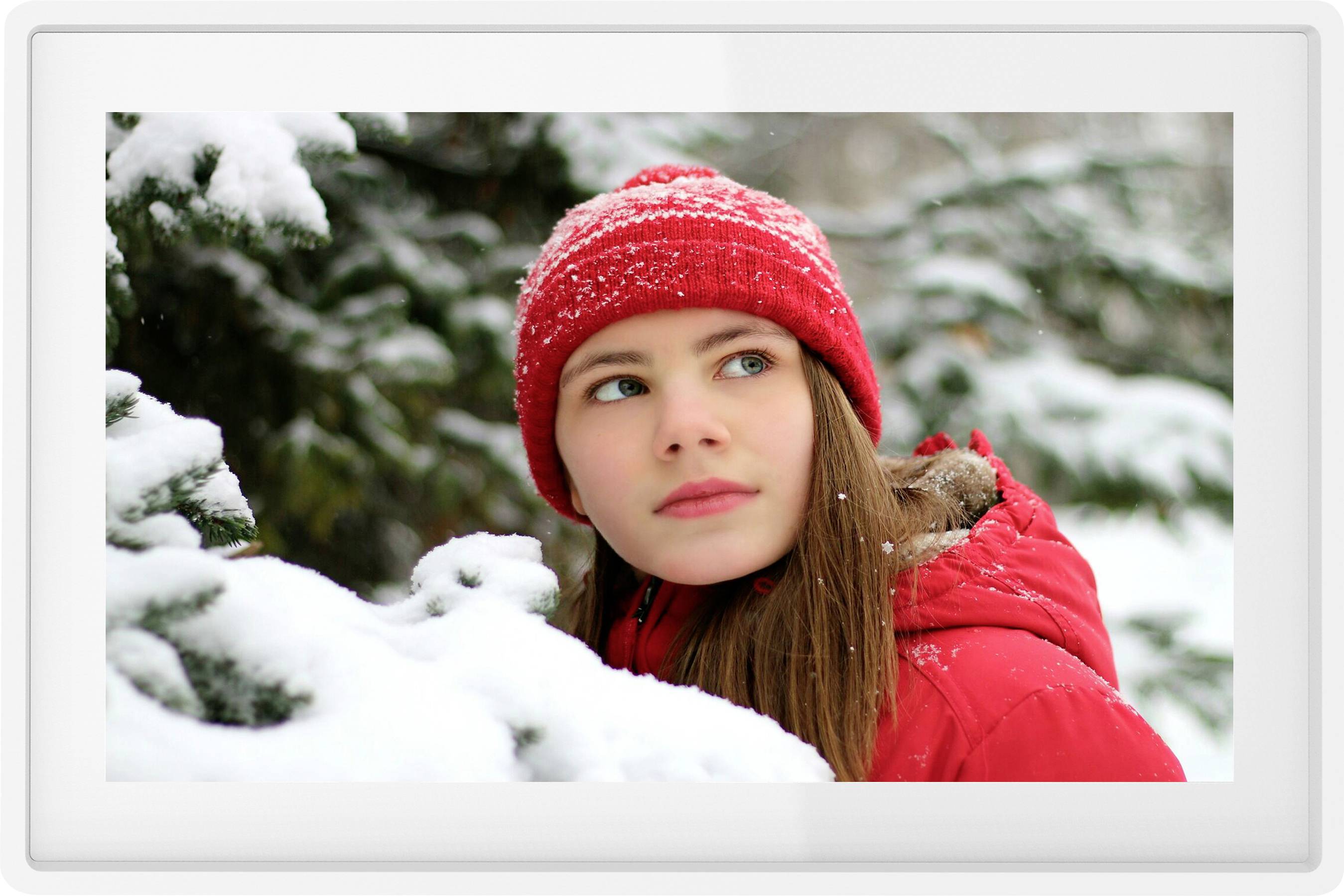 A young woman in red winter clothing stands in a snow-covered forest, gazing thoughtfully to the side.