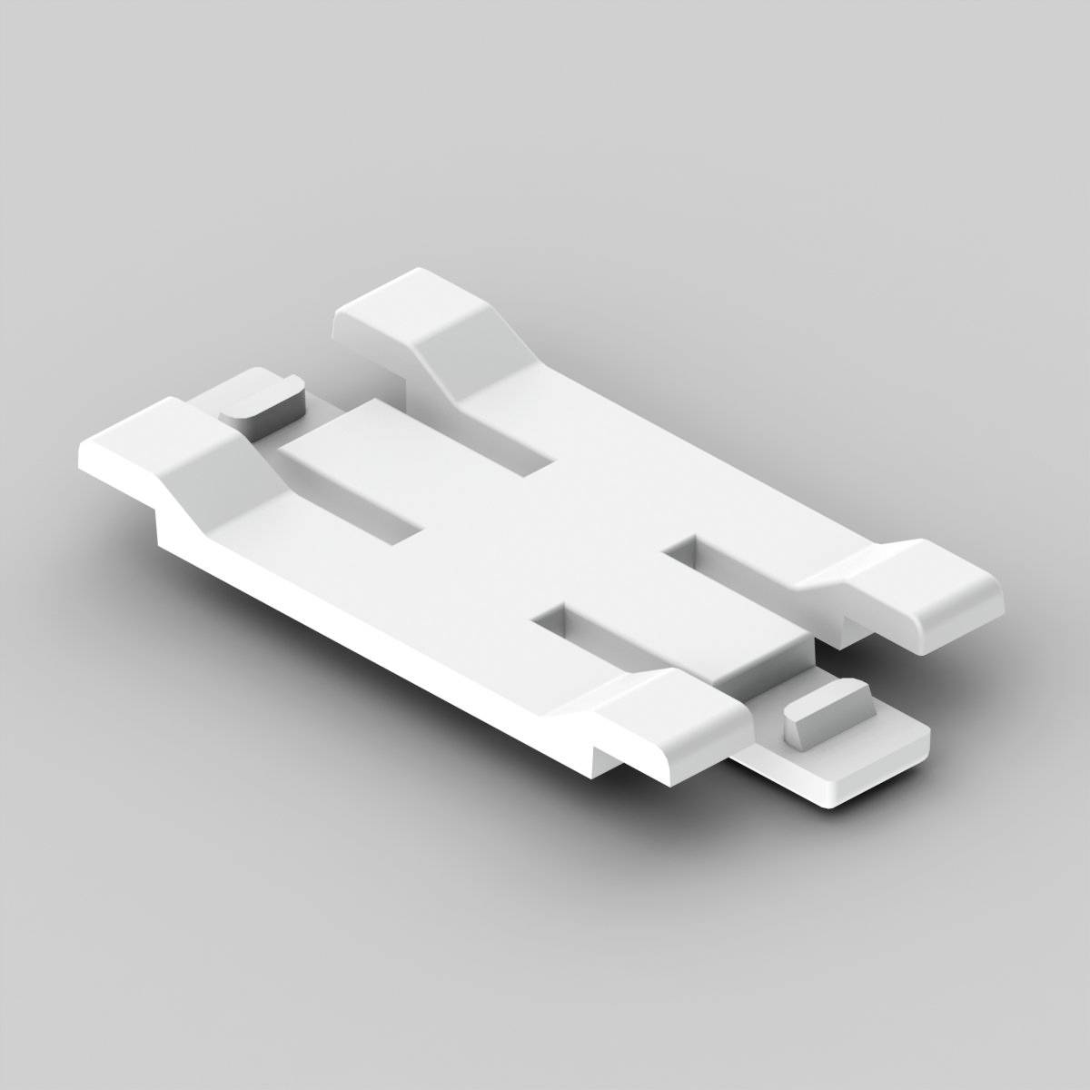A white plastic component with four mounting brackets is resting on a grey surface.