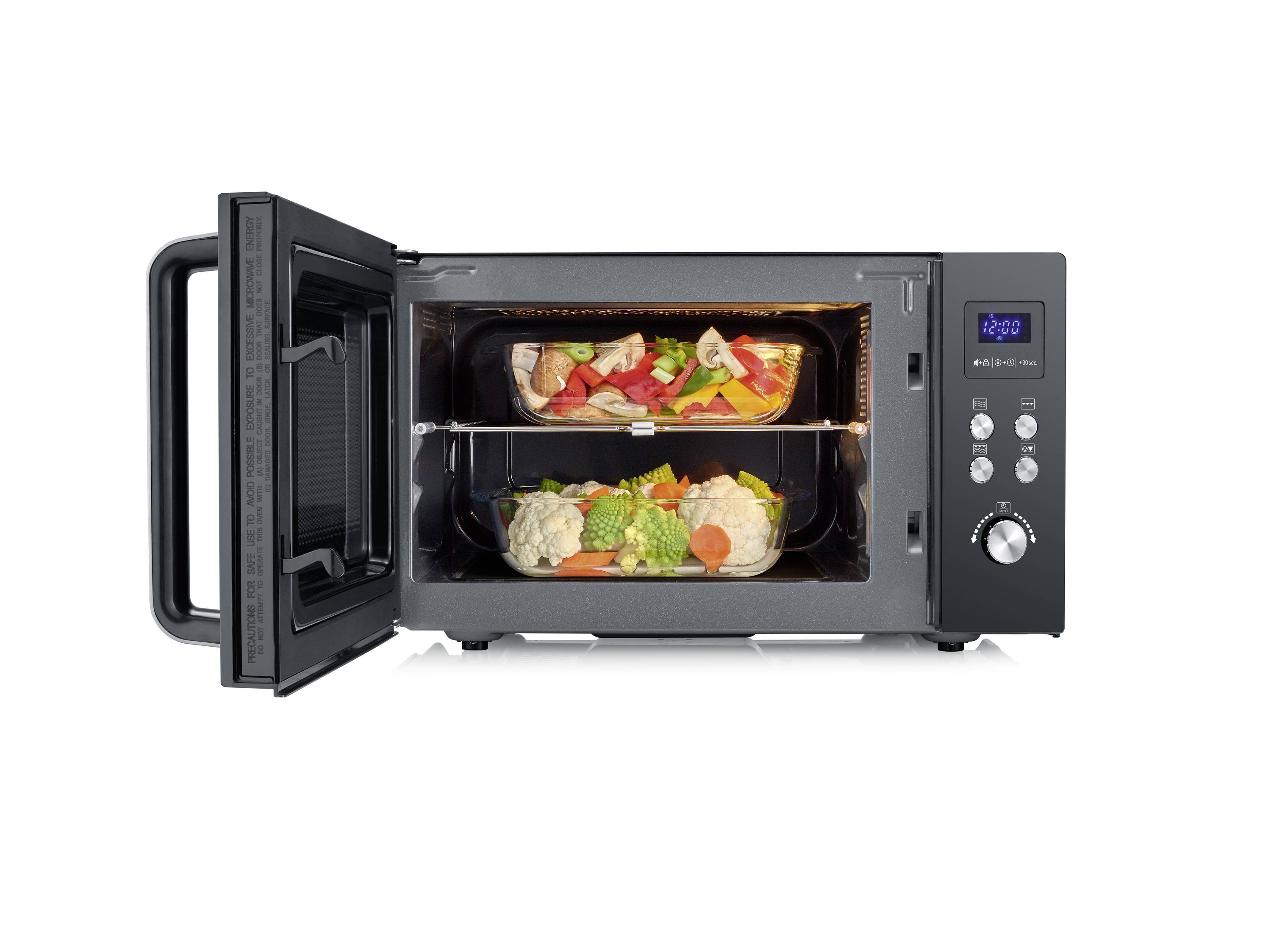 A black convection oven with an open door, showing two baking trays with vegetables and meat.