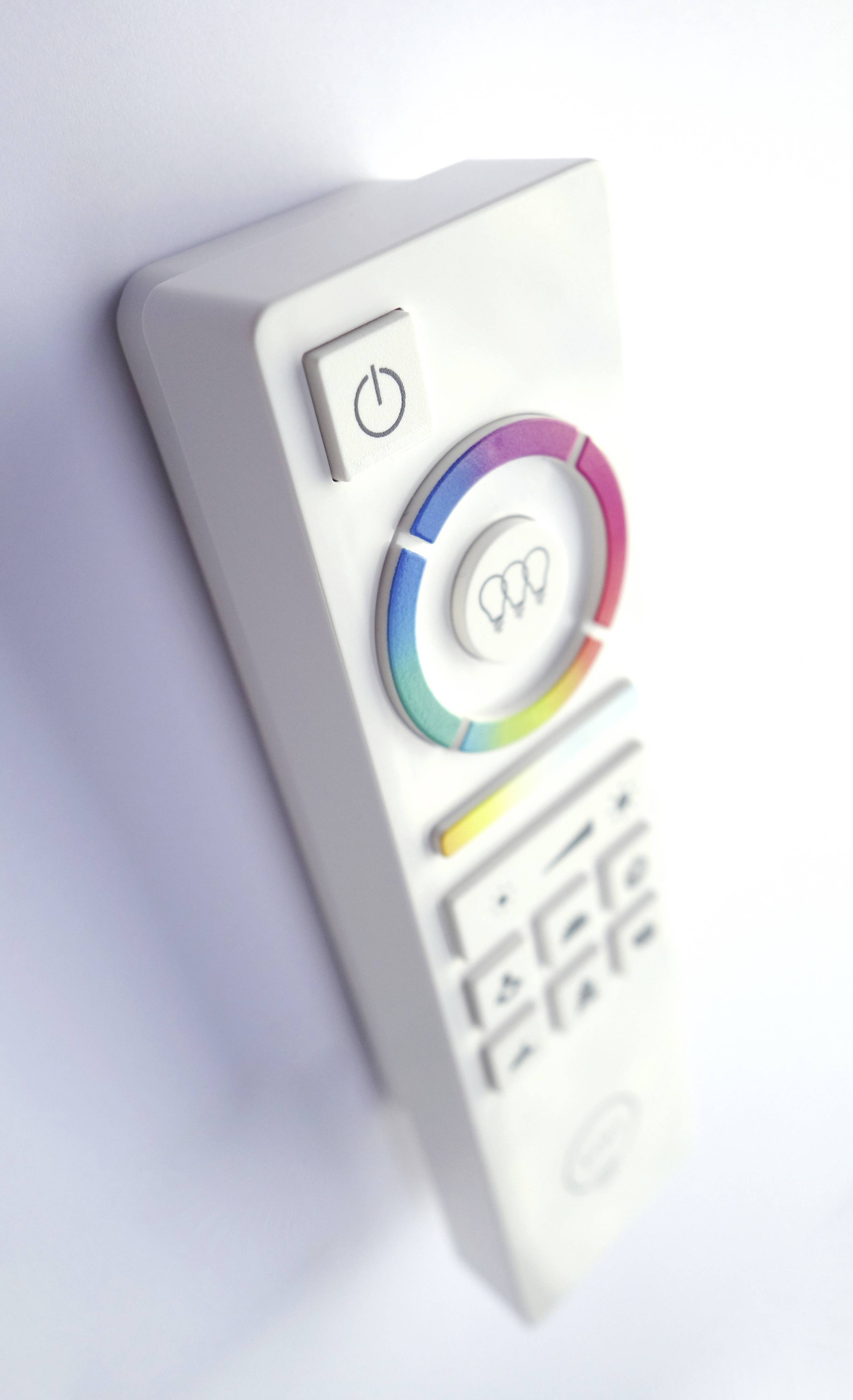White remote control with a colourful colour wheel and multiple buttons, including a large power on/off button at the top.