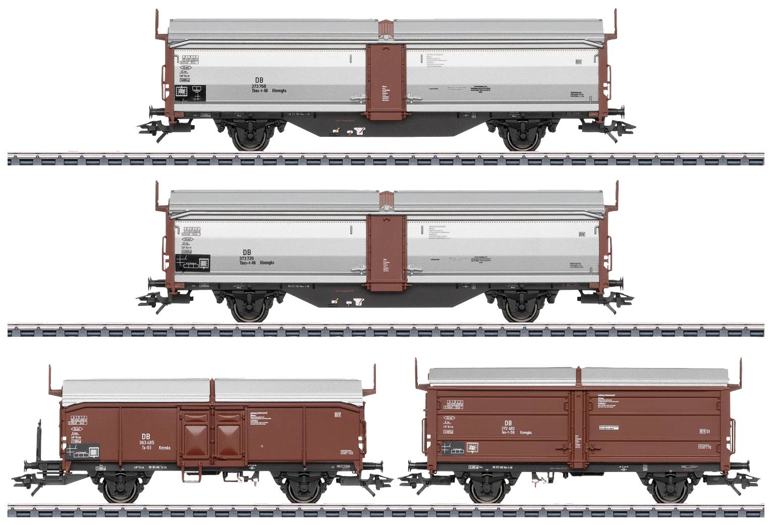 Four freight train wagons on parallel tracks. Each wagon is painted differently, two in red and two in grey-red.