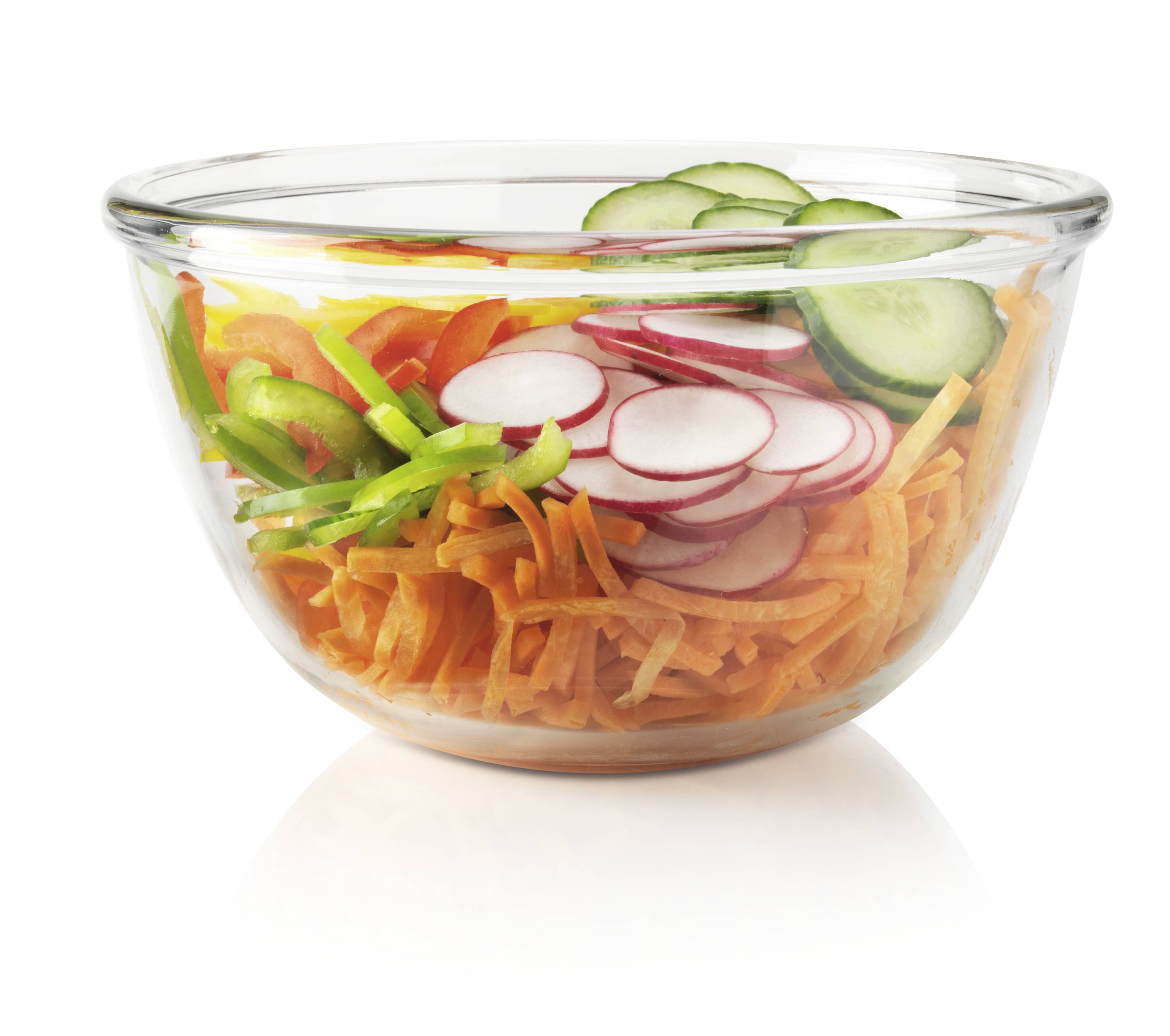 A glass jar containing chopped salad holds carrots, radishes, cucumbers and peppers. Freshly and colourfully arranged.