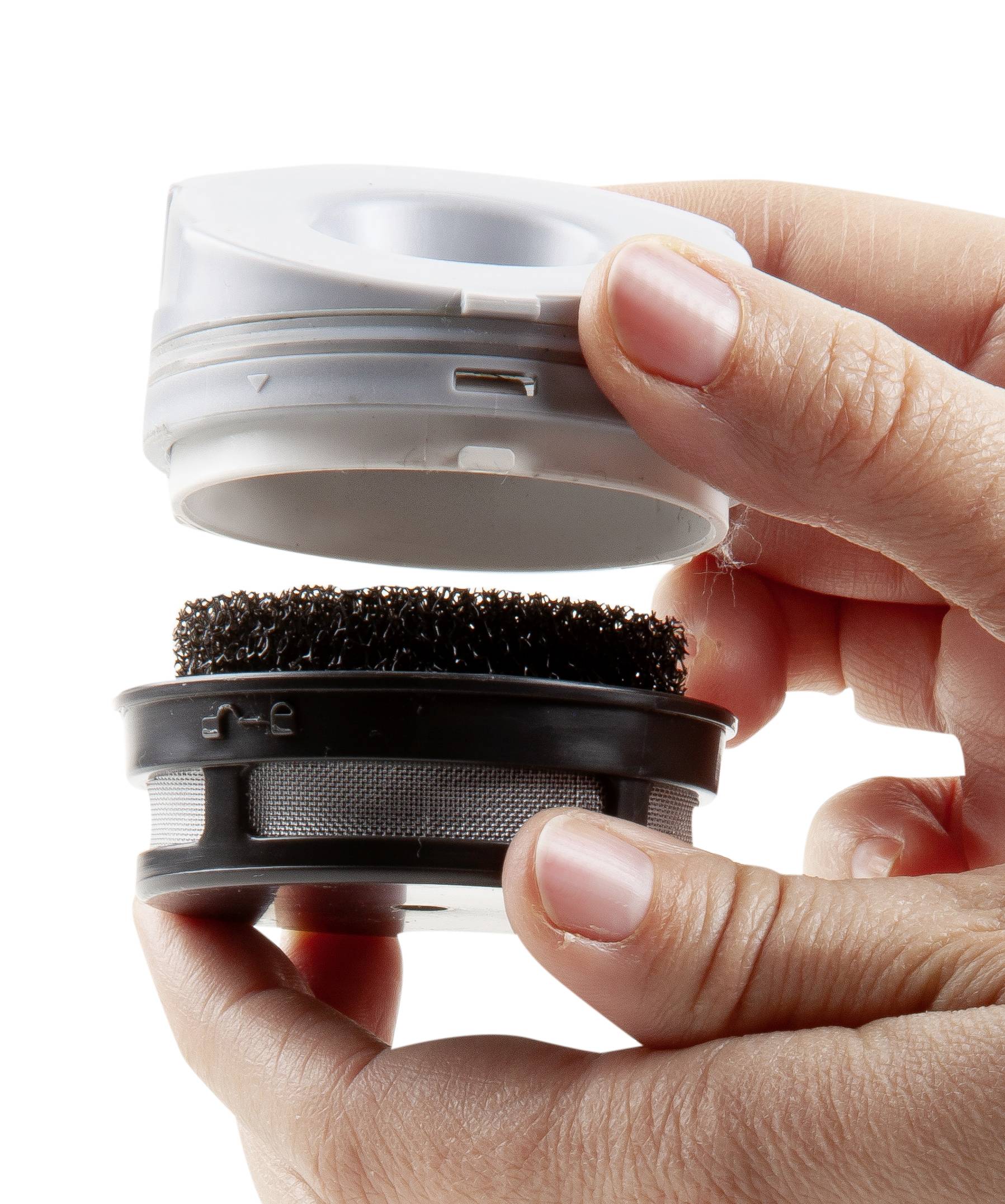 Two hands are holding a coffee capsule system with a removable, black filter.
