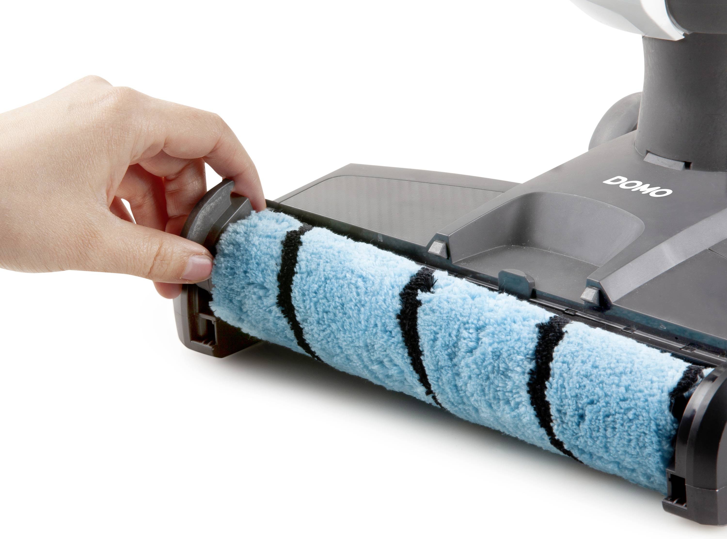A hand removes a rotating brush from a vacuum cleaner head. The brush is blue with black stripes.