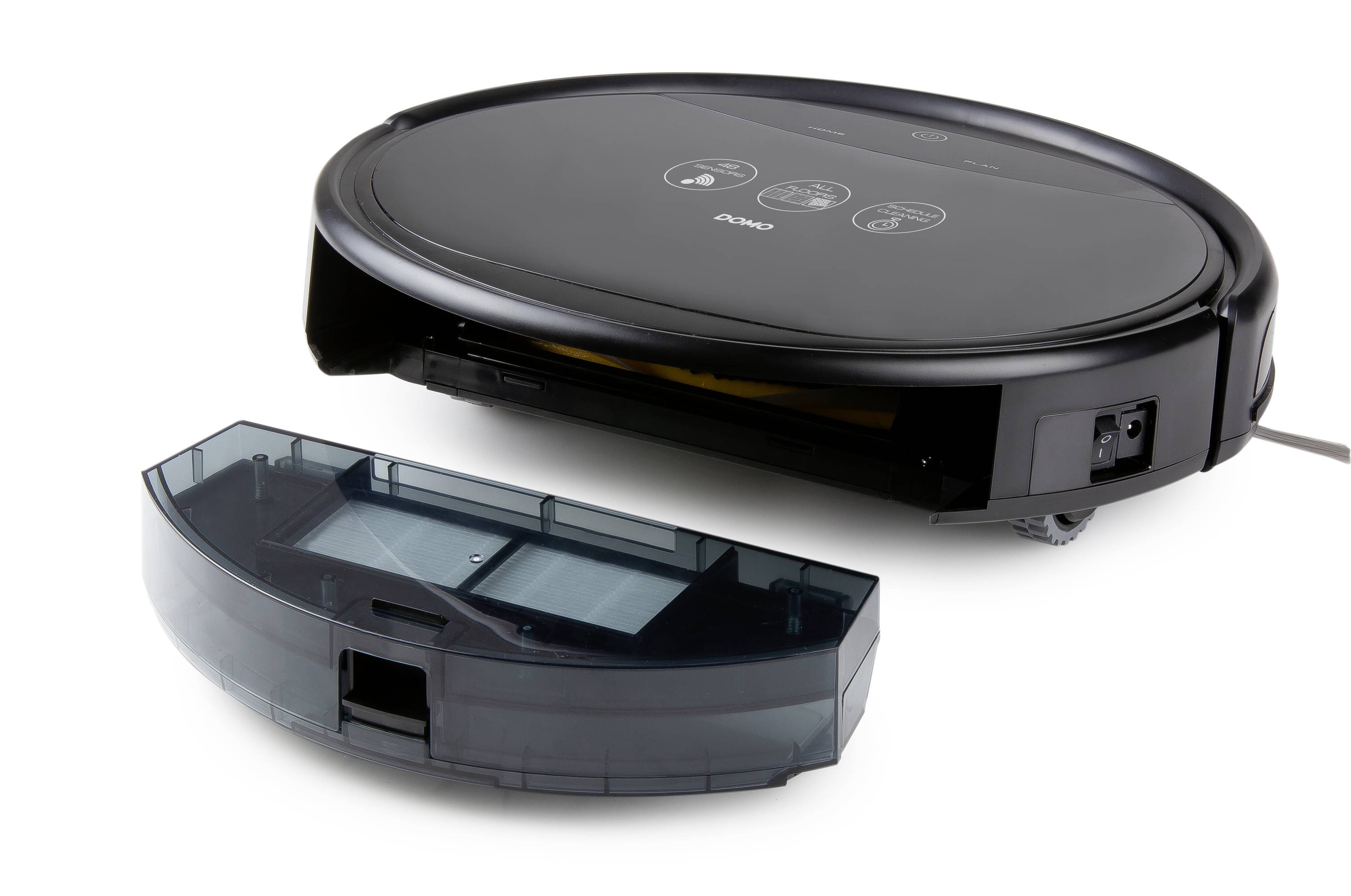 A black robot vacuum with its dust container removed is lying on a white surface.