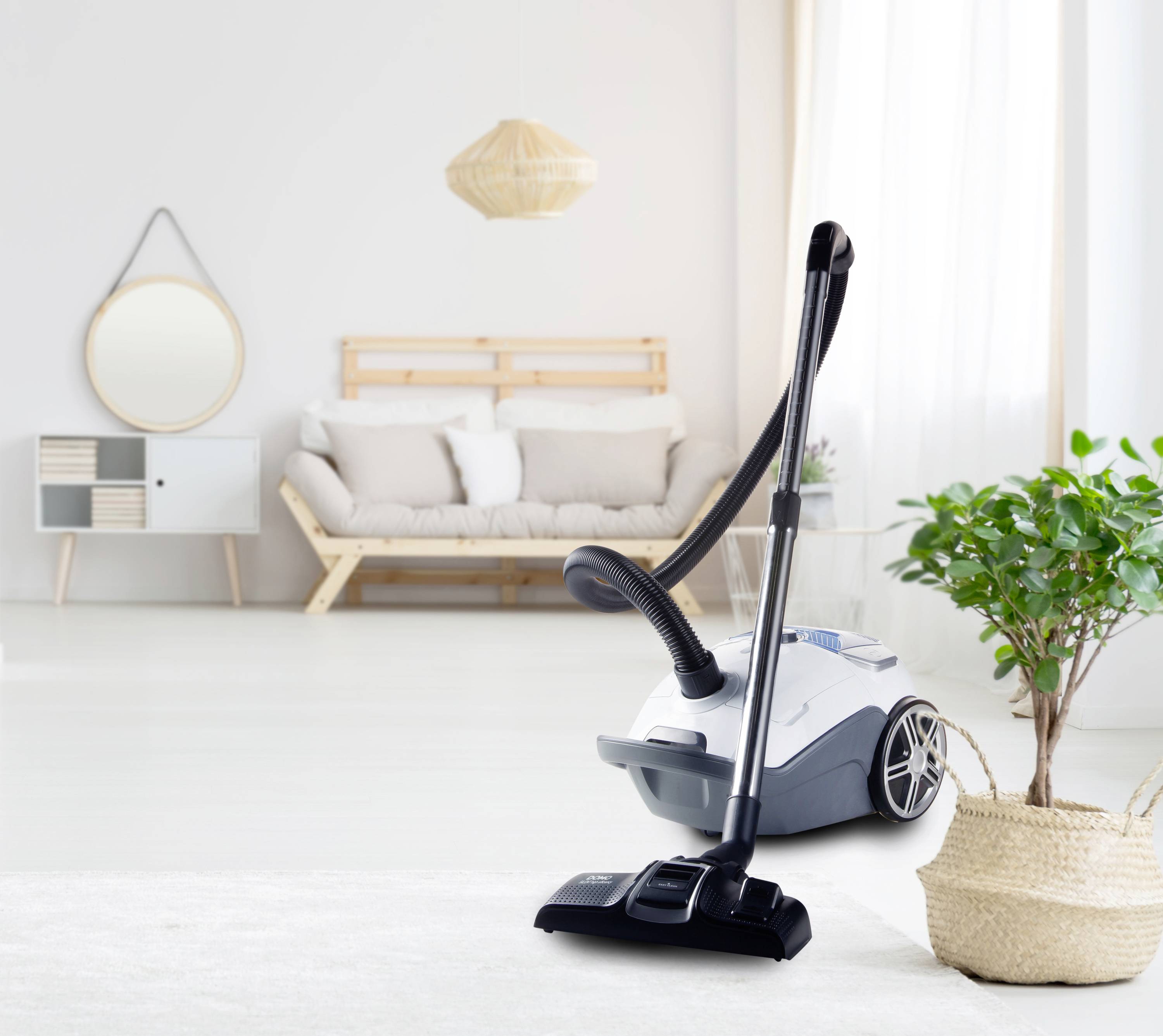 Vacuum cleaner in a modern living room with a grey sofa and green plant. Minimalist design with natural wood accents.