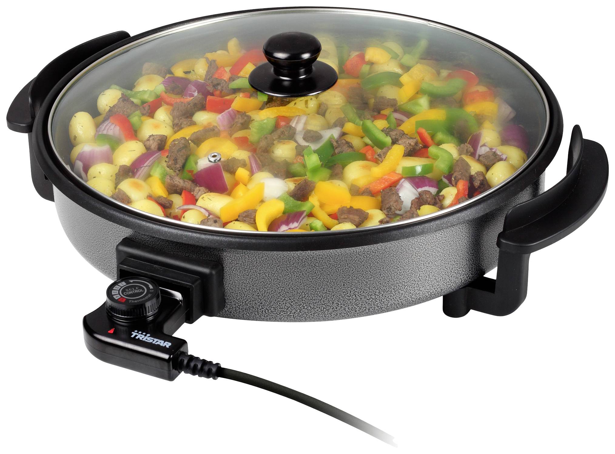 An electric roasting pan with colourful vegetables and meat, covered by a glass lid. Heated by a cable on the side of the appliance.