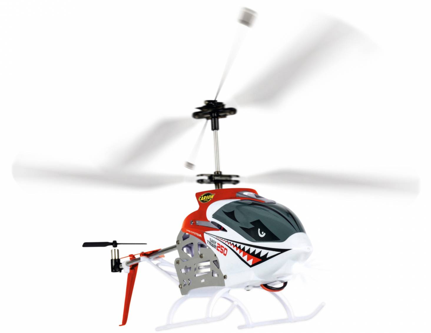 A model helicopter with a red and white design and a shark mouth decal is flying with rotating rotor blades.