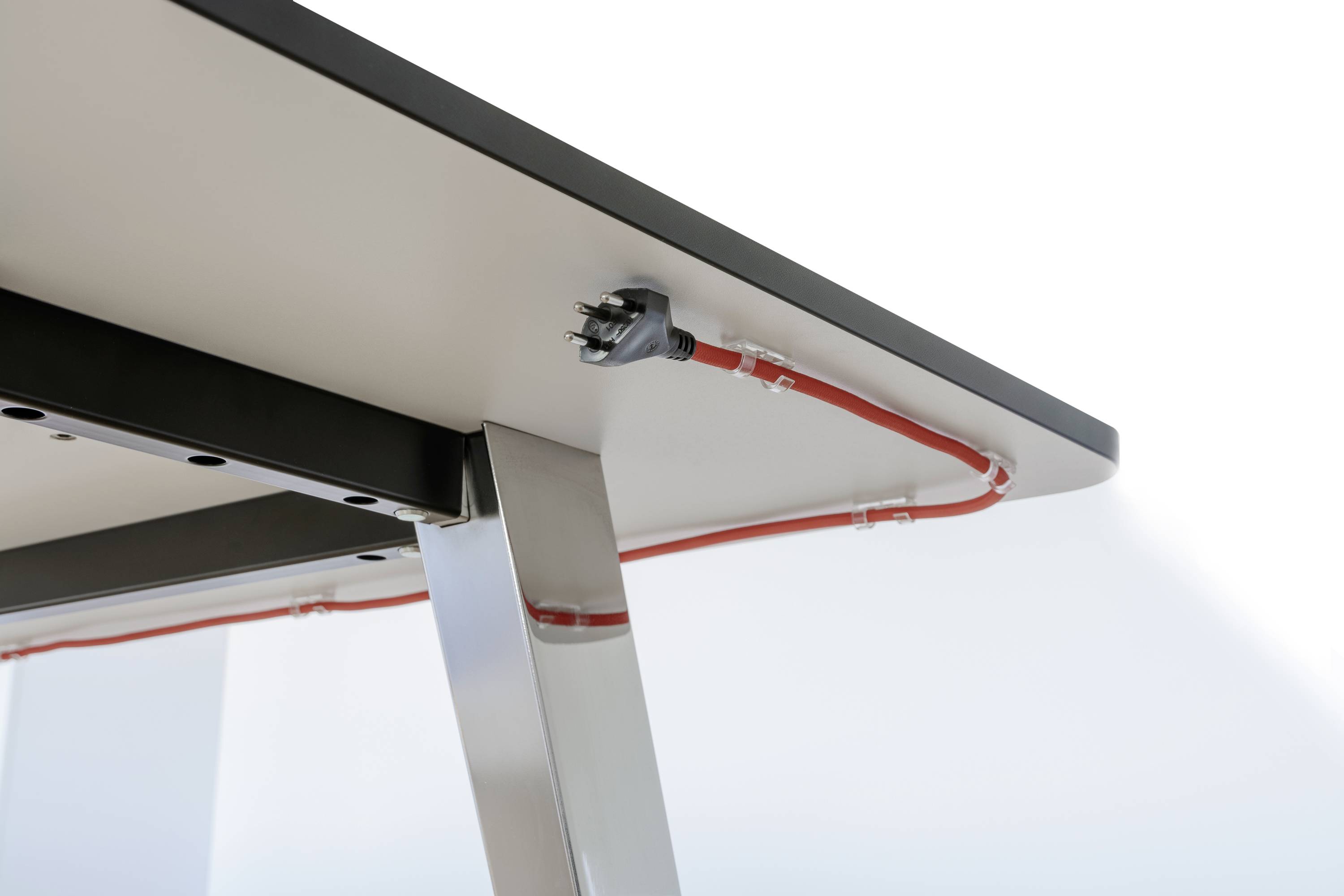 Socket on the underside of a table, cable routed through a cable trunking.