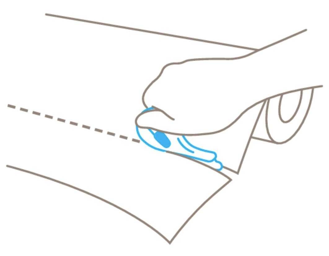 A hand cuts along a dotted line on a sheet of paper using a craft knife.