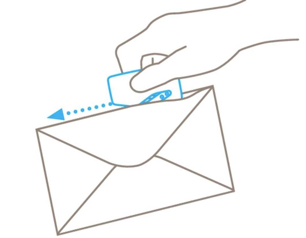 A hand is inserting a blue card with a chip into an envelope.