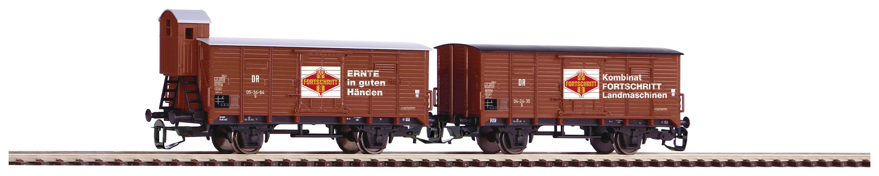 A model train with two brown goods wagons on rails, both with the inscription 'Kombinat Fortschritt Landmaschinen' and 'Harvest in Good Hands'.