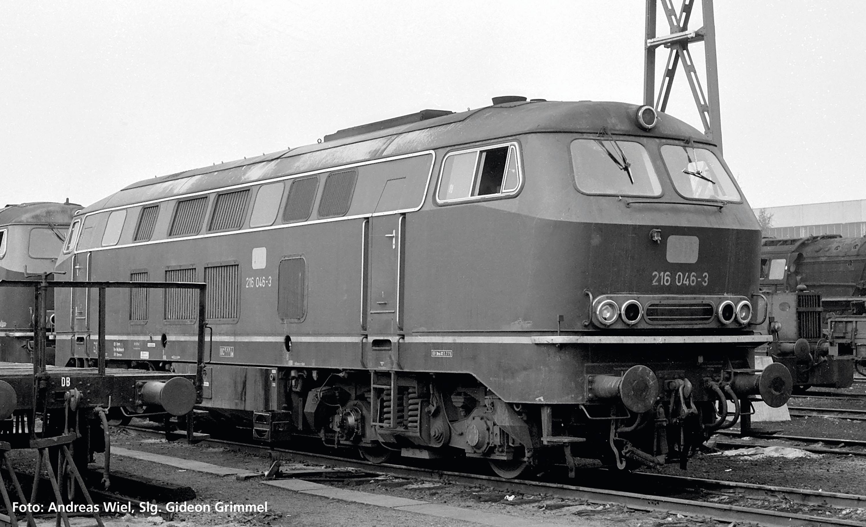 A historic black and white photograph of a diesel locomotive on a siding, surrounded by tracks and equipment.