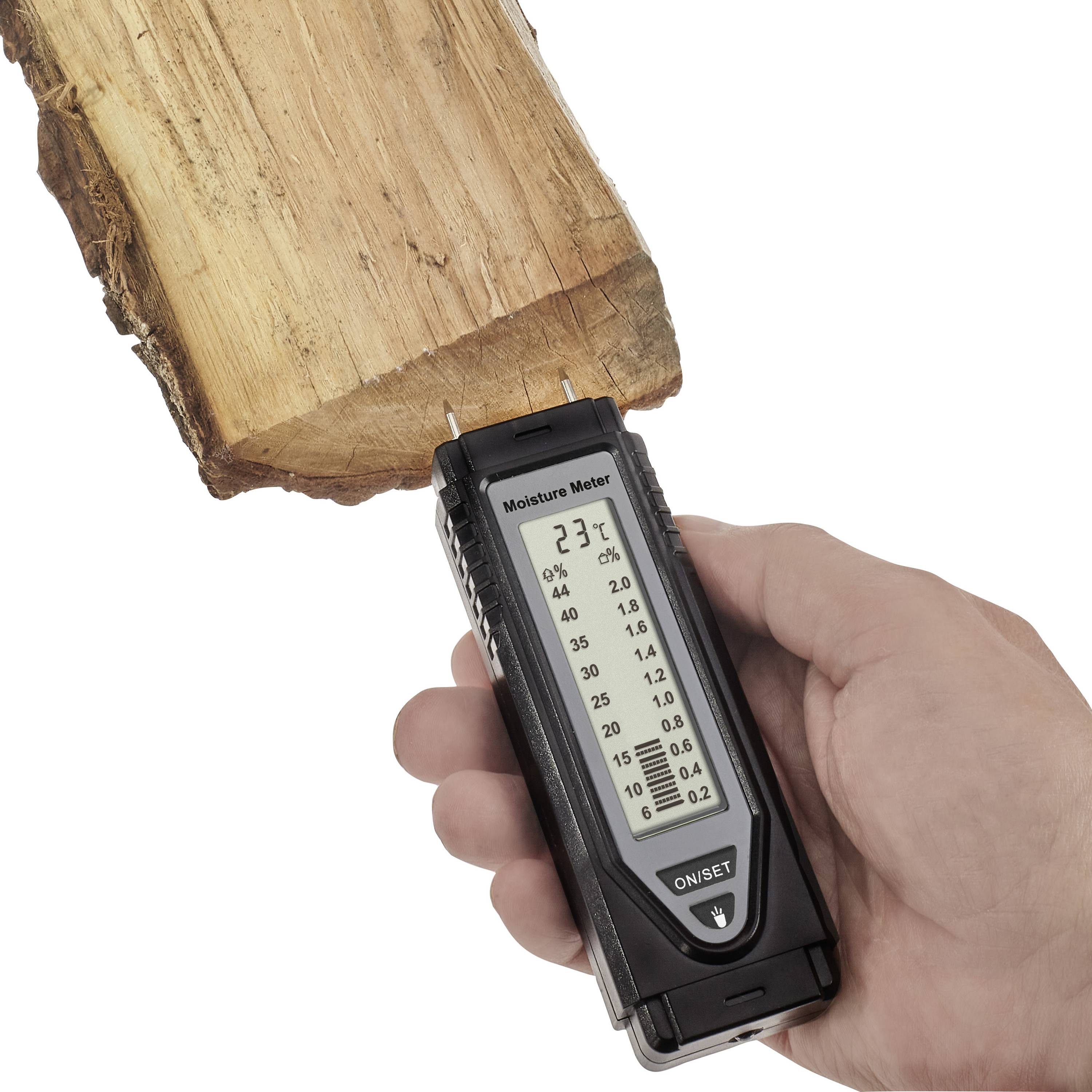 A hand is holding a moisture metre against a piece of wood. The display shows 23% moisture content.