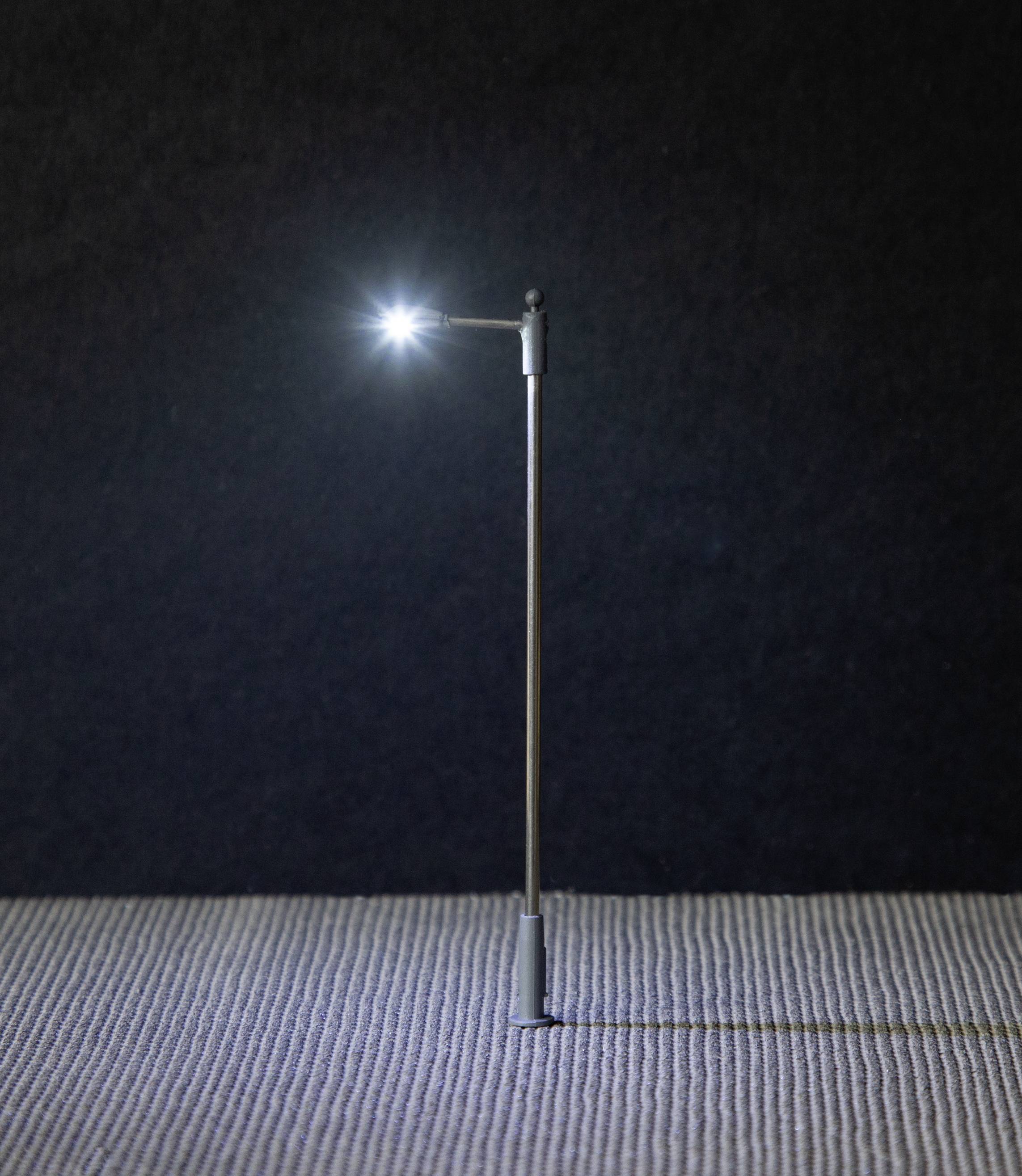 A small lamp glows on a textured surface in a dimly lit room.