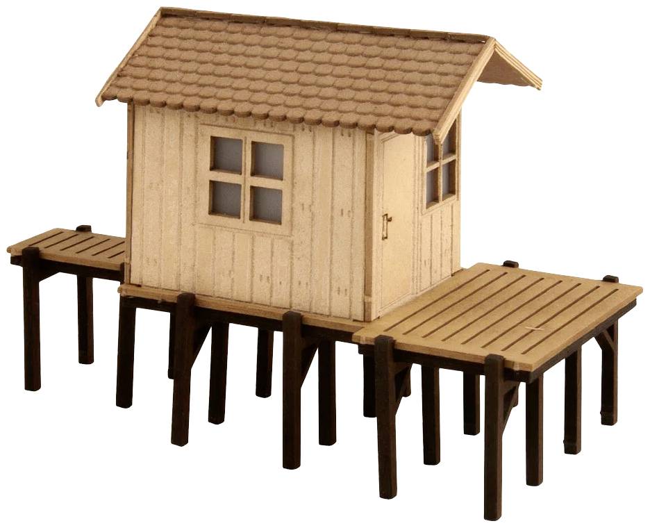 A small, wooden model house stands on stilts. It has a gabled roof, a window on the front, and is surrounded by a platform.