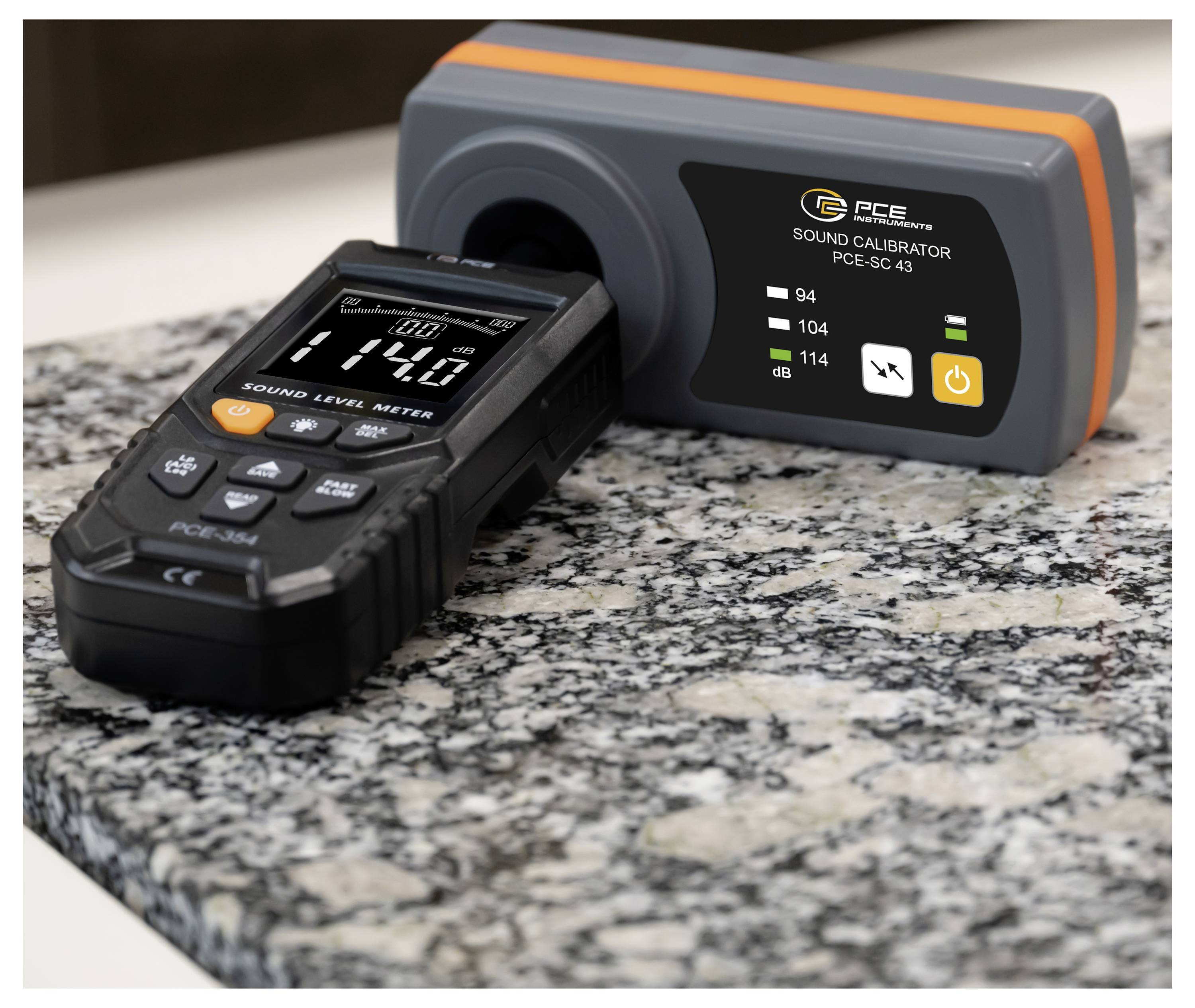 Sound level meter docked in a PCE sound calibrator on a granite countertop, showing a calibration setup for audio measurement.