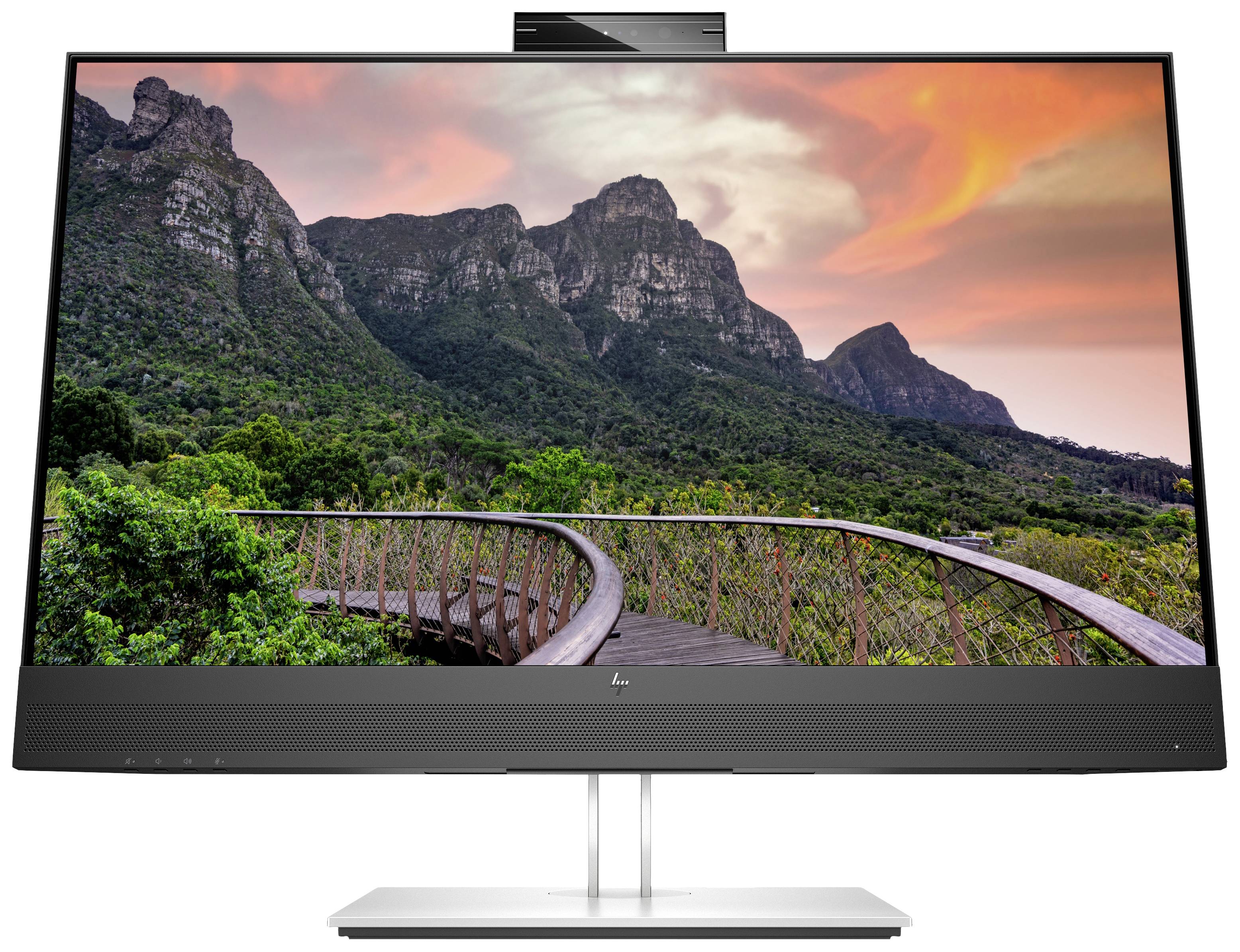 A monitor displays an image of a wooden boardwalk winding through green vegetation, with mountains and a red sky in the background.