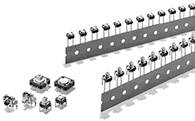 Small electronic components arranged in a row on a strip tape, some individually positioned; typical configuration in manufacturing.