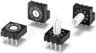 Four black rotary switches with white handles and numbers from 0 to 9, positioned on a light surface, show different positions.