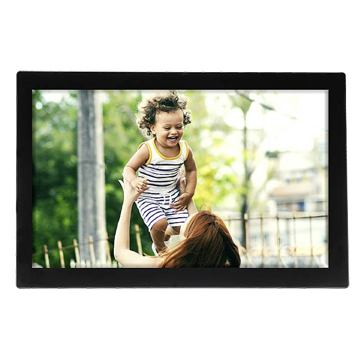 An adult person lifts a laughing child into the air. The child is wearing a striped babygro. The background shows blurred green foliage.
