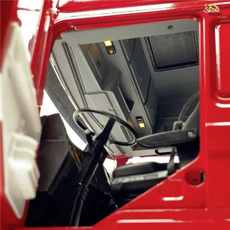 Red lorry cabin with detailed interior view, steering wheel and seats visible.