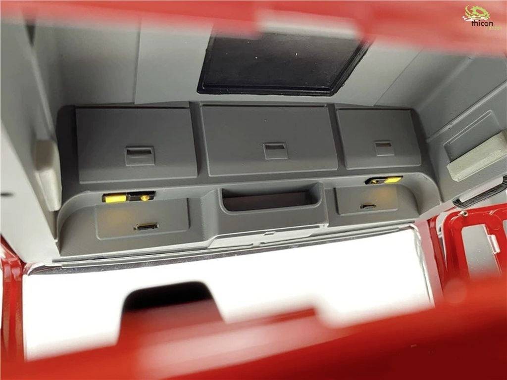 View of the interior of a model vehicle cabin with grey storage compartments and shelves. Red outer edges of the model are visible.
