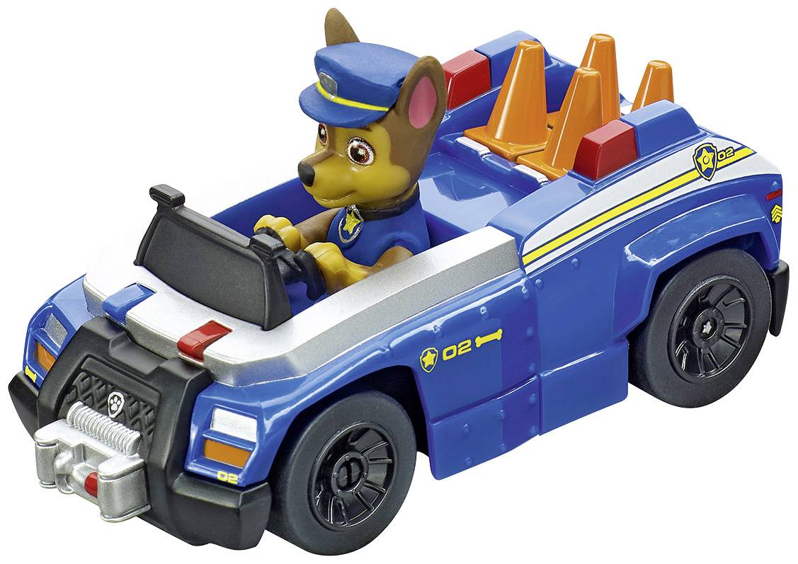 A toy figurine in a blue police car with a dog in a police uniform driving, with orange traffic cones in the background of the vehicle.