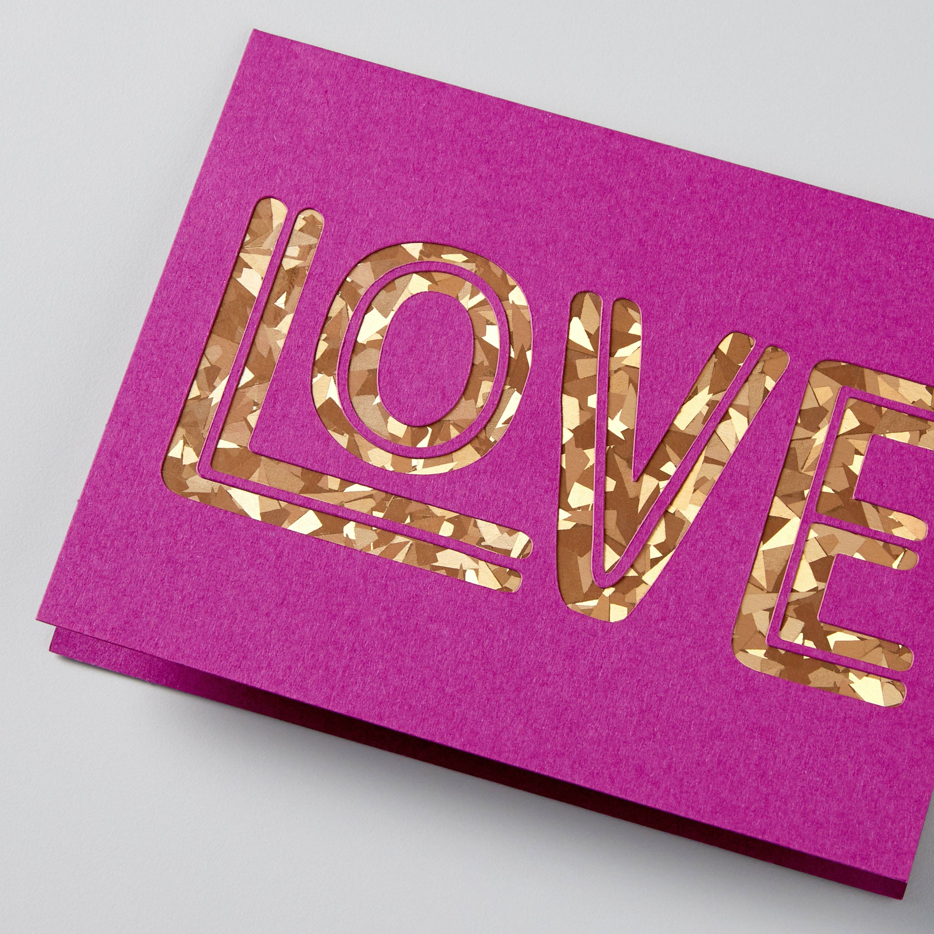 Pink card with the word 'LOVE' in golden, glittery lettering.