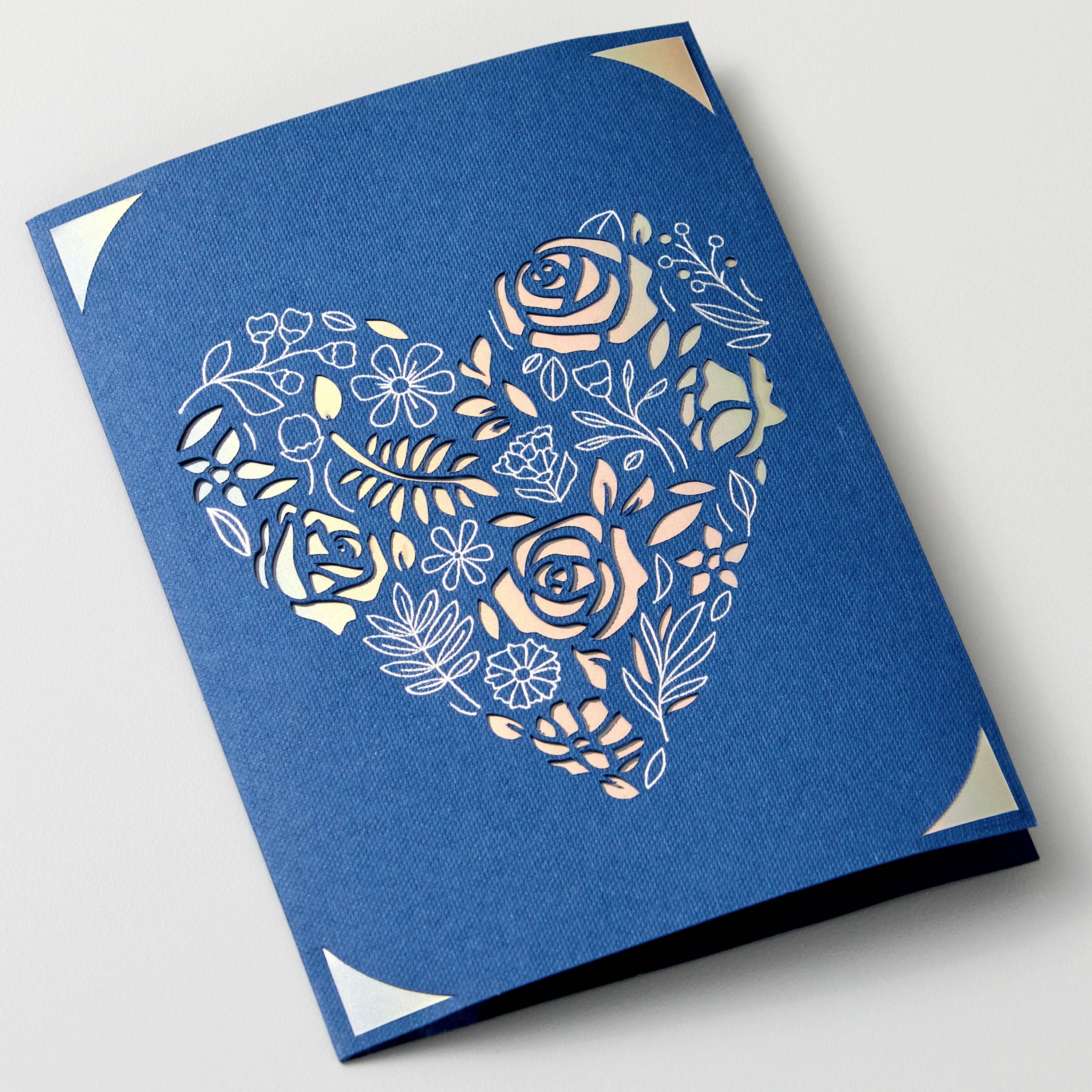 A blue envelope with a heart-shaped, floral cut-out revealing flowers and leaves.