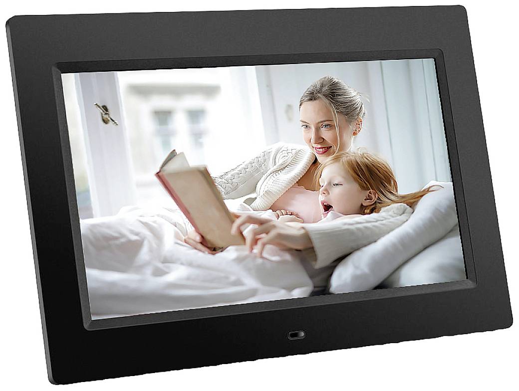 A woman is reading a book to a child on a bed, both laughing and wrapped in a blanket, daylight streaming through the window.