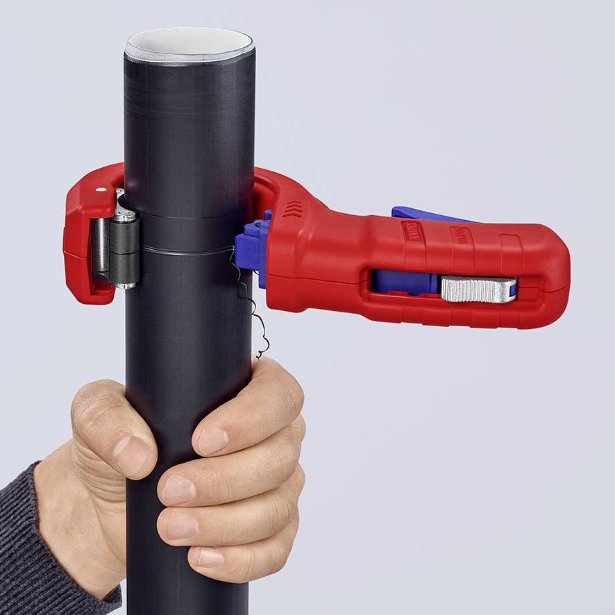 A hand is holding a black pipe with a red pipe cutter gripped around it, ready to cut.