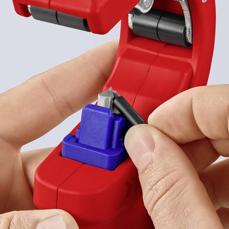 Hands are operating a red cable stripping tool with a blue component and a blade to precisely strip a cable.