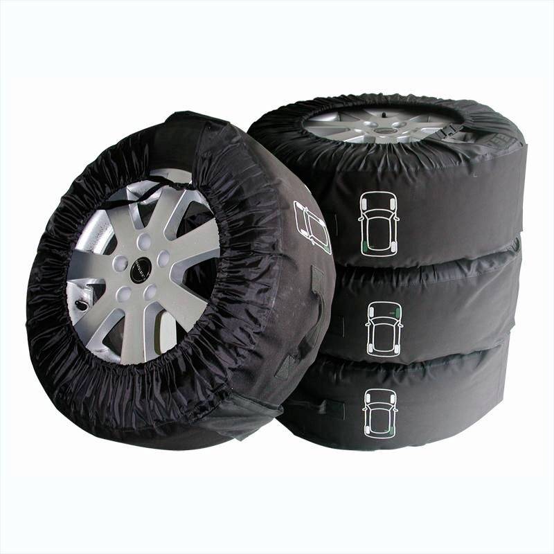 Four car tyres are covered with black protective covers and stacked on top of each other.