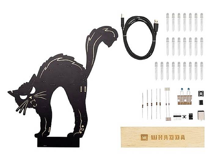 Electronic kit in the shape of a cat with components such as resistors, LEDs, cables, and wooden boards for assembly.