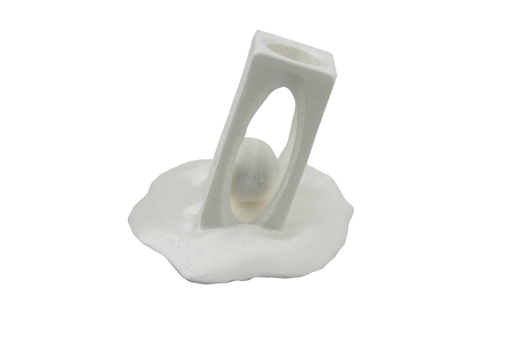 A white 3D-printed holder with an oval opening, through which a white sphere is visible, stands on a wavy base.