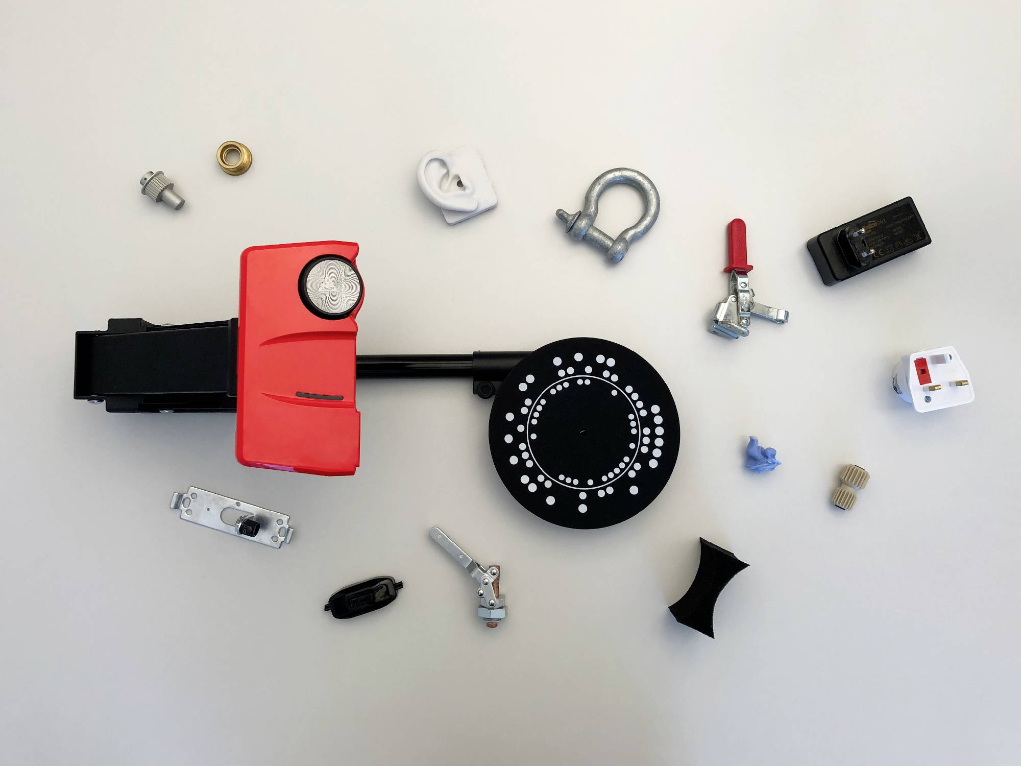 Various mechanical and electronic components, loosely arranged on a table, including gears, switches, and fastening elements.