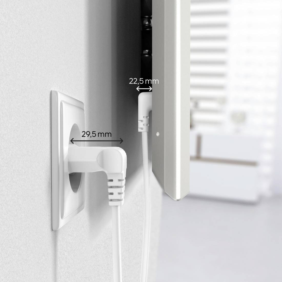 Electrical plug in a wall socket; distance from wall 29.5 mm, distance from furniture 22.5 mm. Background shows blurred room.