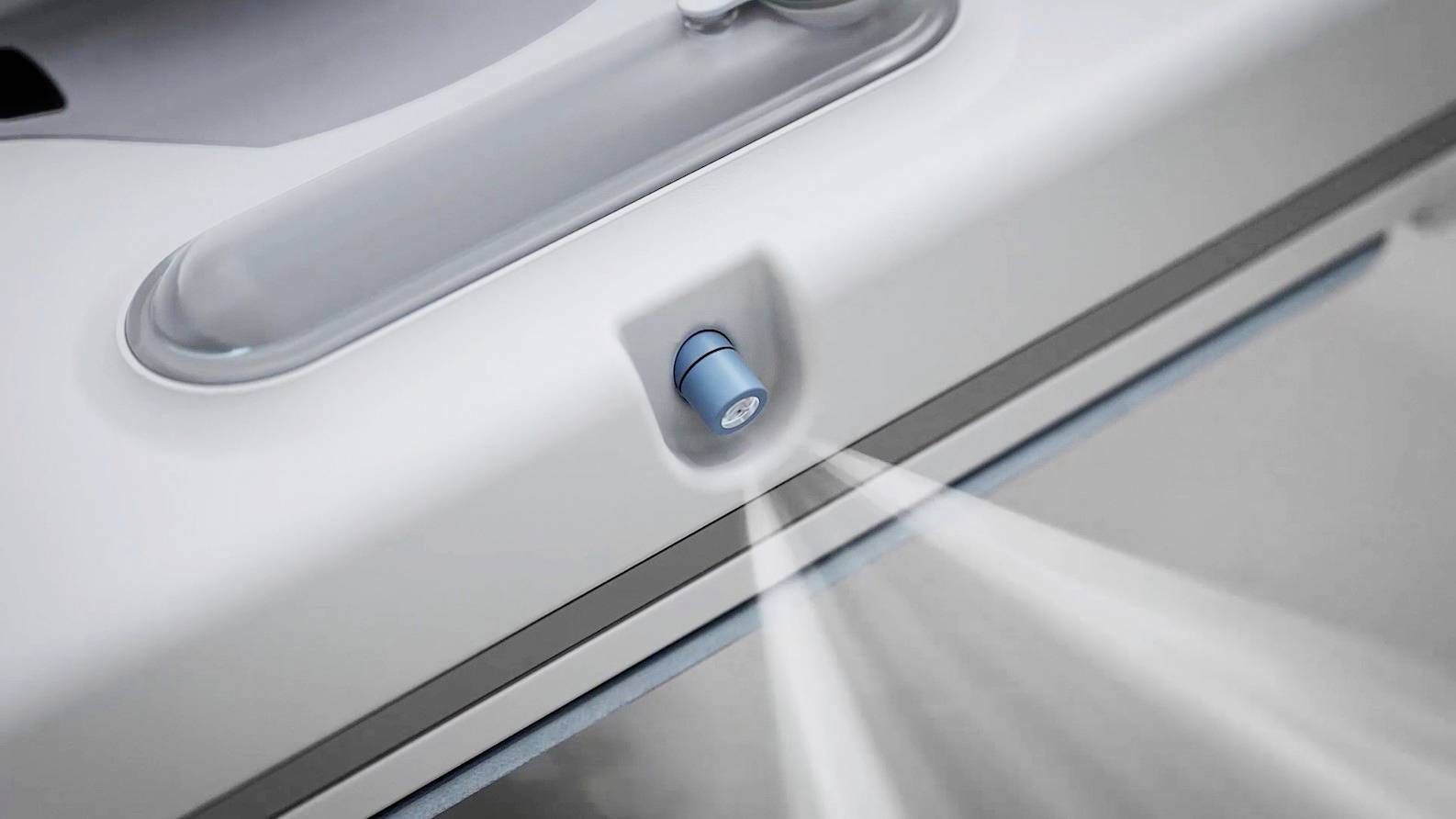 A vacuum cleaner sprays cleaning liquid from a blue nozzle onto a surface to clean it.