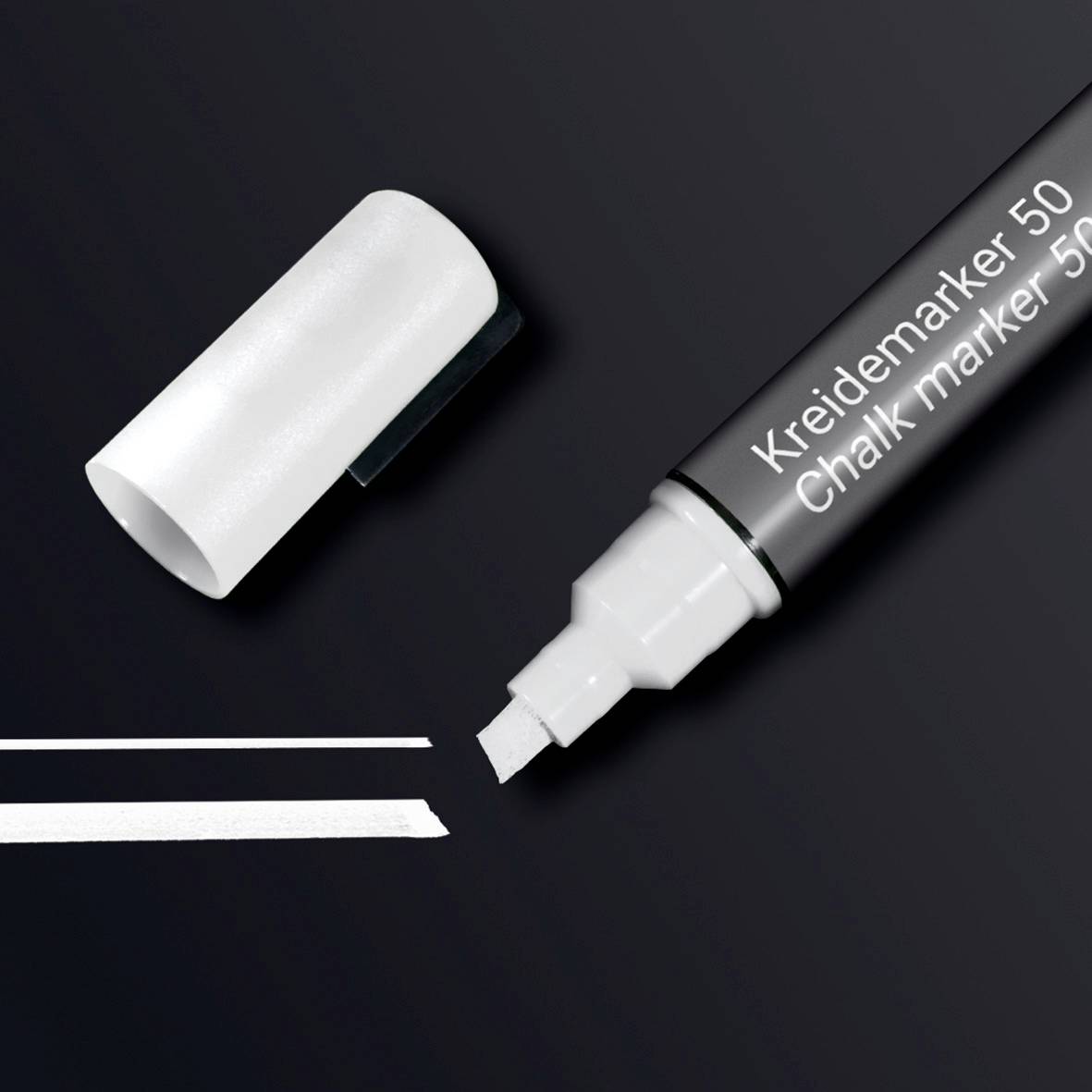 A chalk marker with its lid open lies on a black background. A white line is drawn next to the marker.