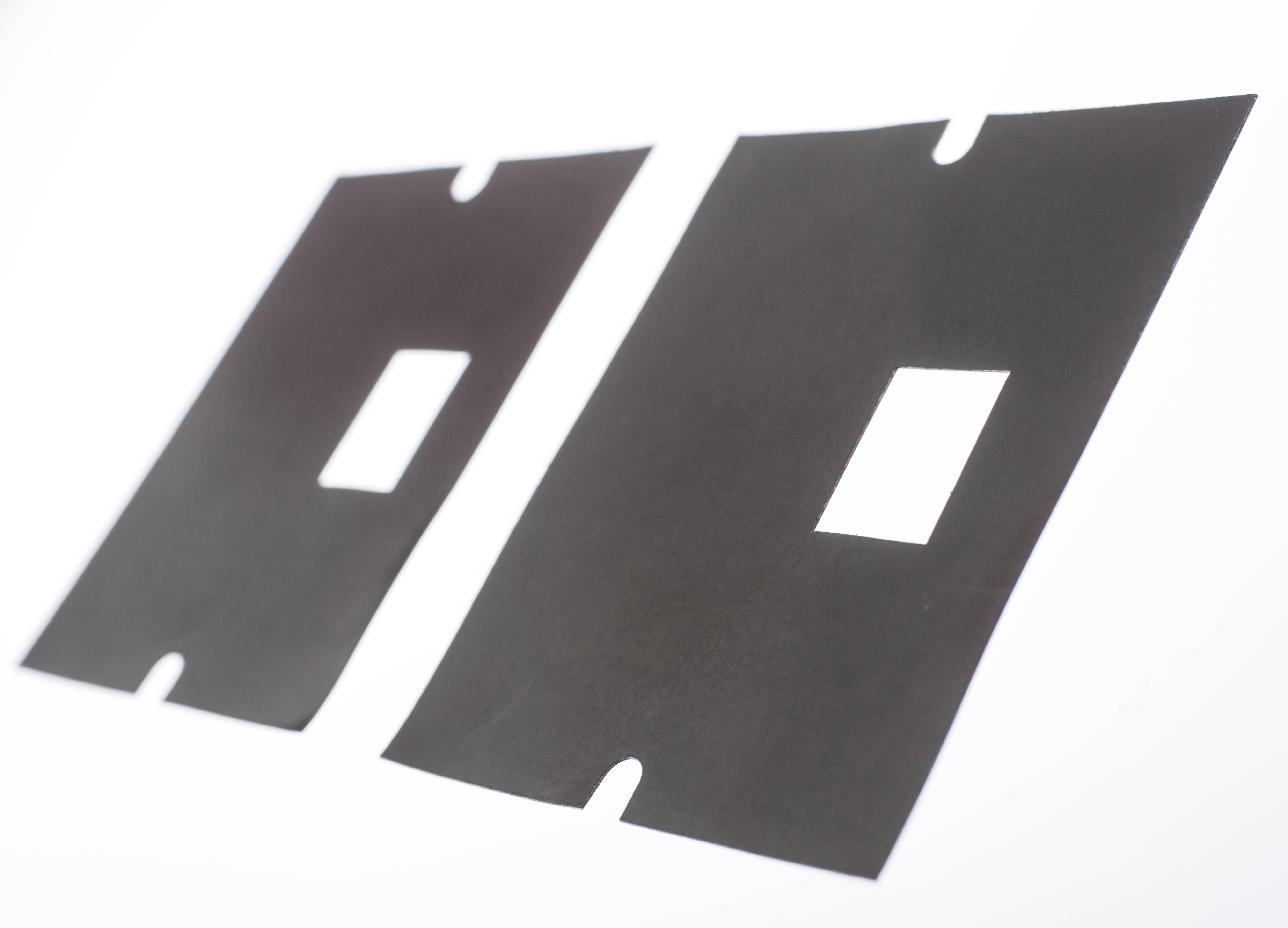 Two black, rectangular rubber mats are lying on a white surface. Each mat has a rectangular cut-out in the centre.